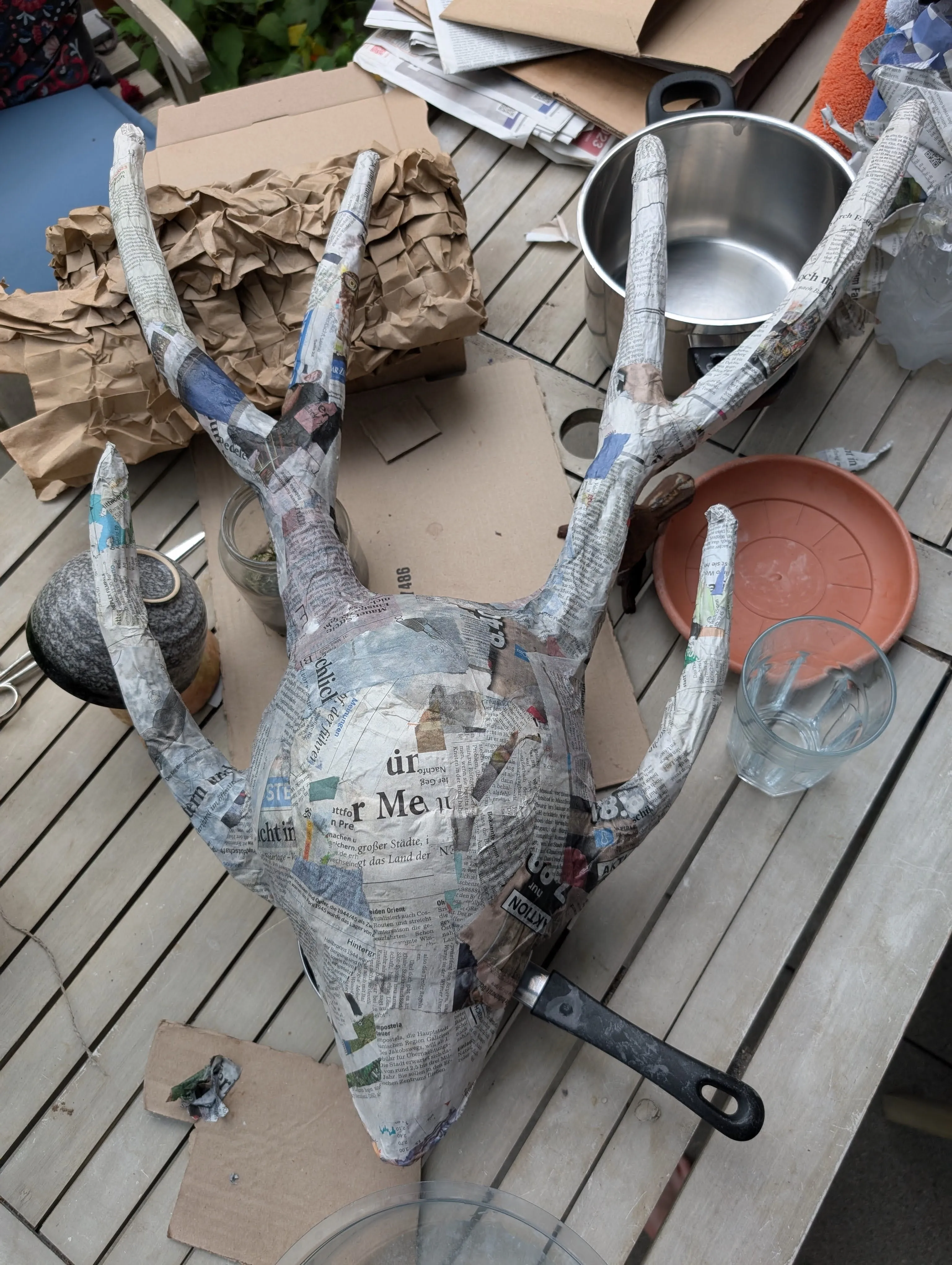 The mask made of paper mache laying on the table outside, with the horns being trimmed down to be more wearable.